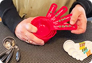A person displaying different sized red measuring cups, white and silver measuring spoons are also on the table.