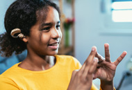 Smiling African-American deaf girl wearing a yellow shirt and using sign language