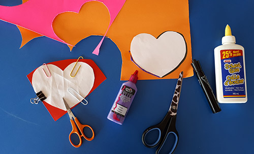 Posterboard, heart pattern, scissor, dimensional fabric paint, liquid school glue, marker, paper clips.