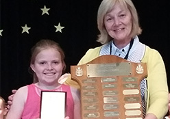 Avery accepting her award on stage with her teacher