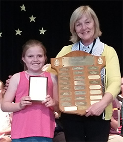Avery accepting her award on stage with her teacher