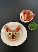 Bunny Sandwich 2 - Bunny face sandwich made from circle cut bread, crusts with strawberries for ears, banana slices and blueberries for eyes, blackberry nose, strawberry mouth and rectangular cut cheese for teeth. Served with apple slices and lettuce greens.