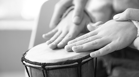 a parent is holding a child's hands to help show them how to play a drum
