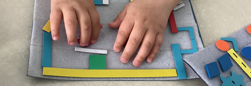 A young student explores a tactile map of his classroom.