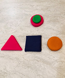 Playdough shapes: The top row has a large pink circle, with a smaller green circle placed on top of it. The bottom row has a large pink triangle, a large purple square and a large orange circle.