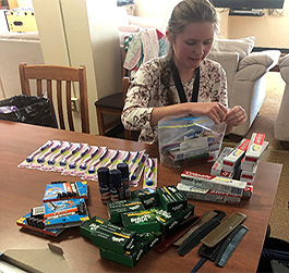 A student sits at a table assembling a hygiene kit.