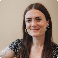 Person with long brown hair wearing hoop earrings and a patterned top.